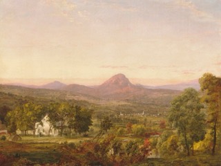 A wide valley of autumn trees and farms below a cone-shaped mountain, under a hazy pink sky.