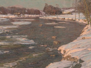 A wide river with floating ice winds between snowy banks, with bare trees and a farmhouse in late winter sunlight.